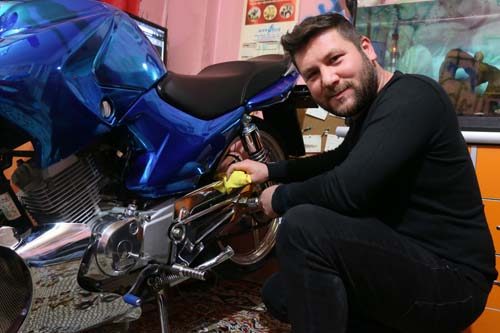 Modifiye motosikletini evinin salonuna park ediyor
