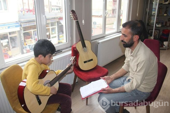 Müzisyen terzi minik ellere nota öğretiyor
