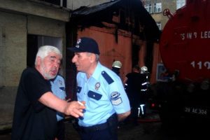 Yanan evini elindeki i&ccedil;ki şişesi ile izledi