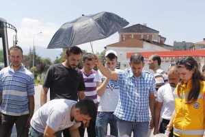 Dakikalarca elinde şemsiye ile başında bekledi
