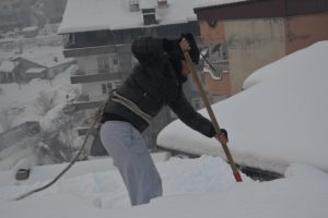 Bellerine halat bağlayıp, &ccedil;atıları kardan temizliyorlar