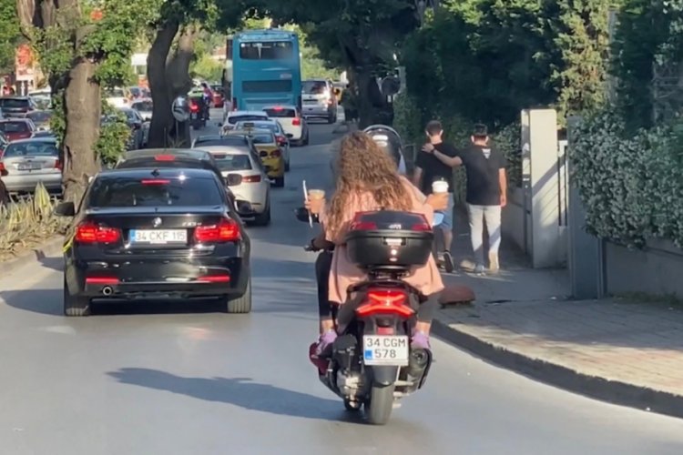 Elinde kahve bardaklarıyla motosiklette yolculuk