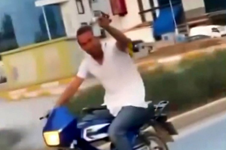 Kasksız motosikletli, elinde i&ccedil;ki dolu bardakla seyretti