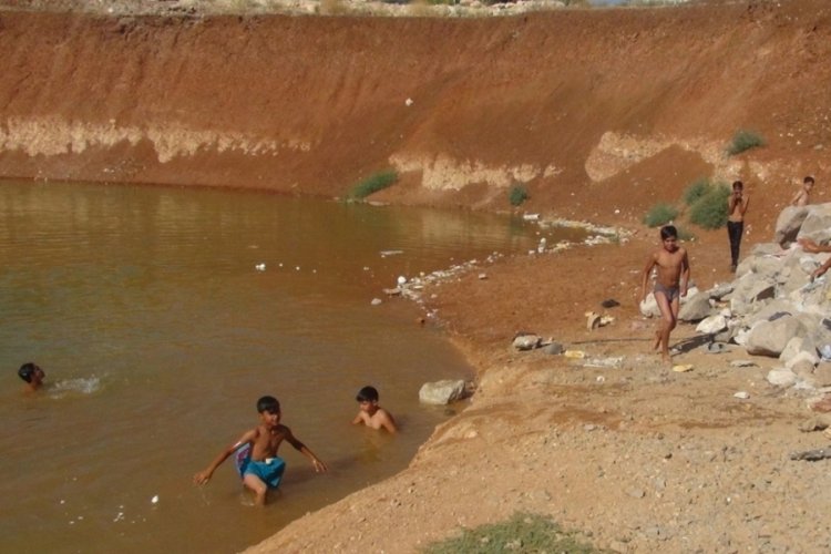 K&uuml;&ccedil;&uuml;k &ccedil;ocuklar inşaat temelindeki kirli suda y&uuml;z&uuml;yor