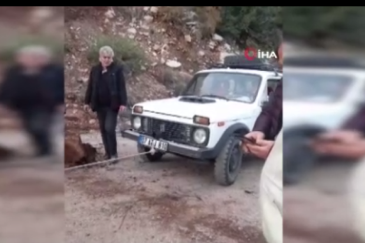 Yola d&uuml;şen kayaları iple araca bağlayıp &ccedil;ektiler