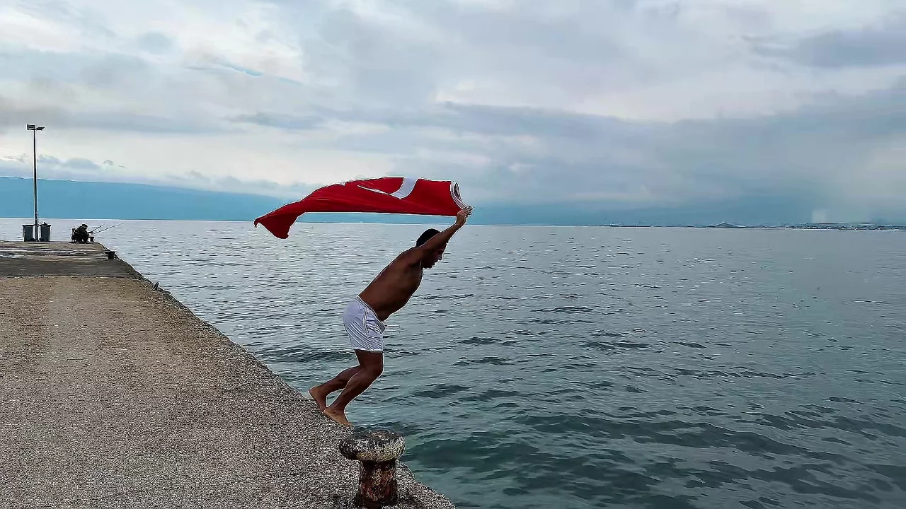 Soğuk ve yağışlı havaya aldırmadı, Türk bayrağıyla denize girdi