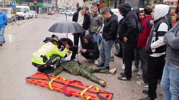 Kadın polis, yaralı ıslanmasın diye başında şemsiyeyle bekledi